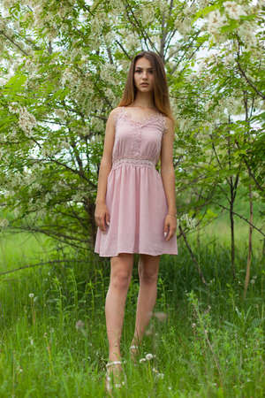 sexual girl has dissolved long hair sunny in the afternoon opposite blossoming white acaciaの写真素材
