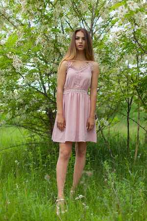 sexual girl has dissolved long hair sunny in the afternoon opposite blossoming white acaciaの写真素材