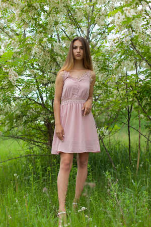 sexual girl has dissolved long hair sunny in the afternoon opposite blossoming white acaciaの写真素材