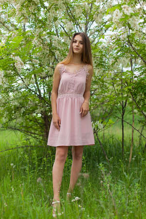 sexual girl has dissolved long hair sunny in the afternoon opposite blossoming white acaciaの写真素材
