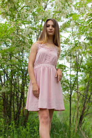 sexual girl has dissolved long hair sunny in the afternoon opposite blossoming white acaciaの写真素材