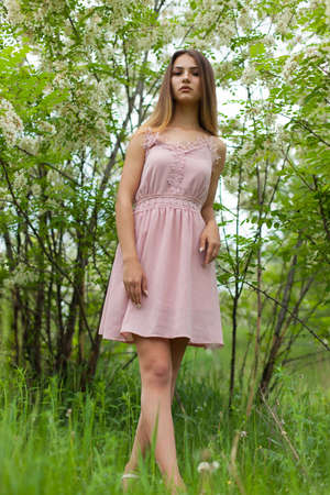 sexual girl has dissolved long hair sunny in the afternoon opposite blossoming white acaciaの写真素材