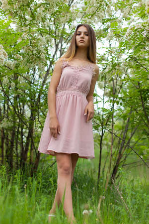 sexual girl has dissolved long hair sunny in the afternoon opposite blossoming white acaciaの写真素材