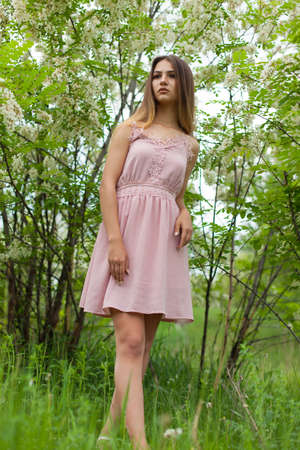sexual girl has dissolved long hair sunny in the afternoon opposite blossoming white acaciaの写真素材