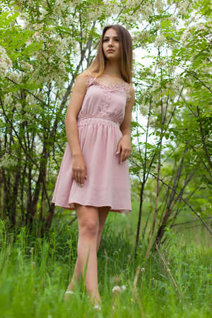 sexual girl has dissolved long hair sunny in the afternoon opposite blossoming white acaciaの写真素材
