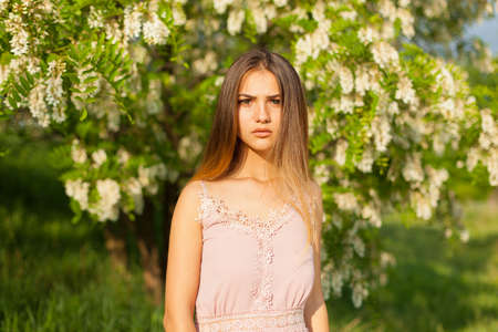 close-up portrait of a beautiful young girl in around white acacia in the springの写真素材