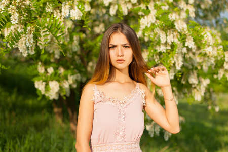 close-up portrait of a beautiful young girl in around white acacia in the springの写真素材