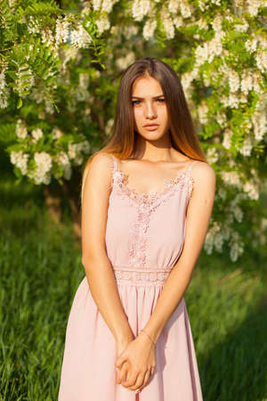 sexual girl has dissolved long hair sunny in the afternoon opposite blossoming white acaciaの写真素材