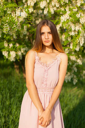 sexual girl has dissolved long hair sunny in the afternoon opposite blossoming white acaciaの写真素材