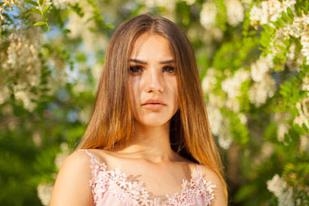 close-up portrait of a beautiful young girl in around white acacia in the springの写真素材