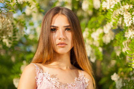 close-up portrait of a beautiful young girl in around white acacia in the springの写真素材