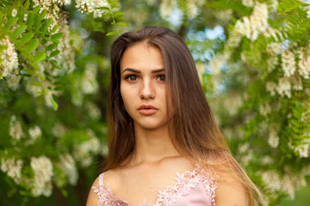 close-up portrait of a beautiful young girl in around white acacia in the springの写真素材
