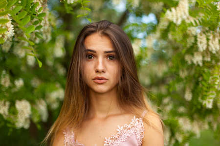 close-up portrait of a beautiful young girl in around white acacia in the springの写真素材
