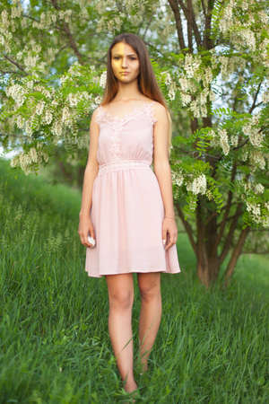 sexual girl has dissolved long hair sunny in the afternoon opposite blossoming white acaciaの写真素材