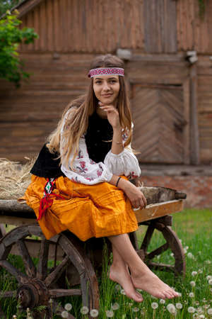 Beautiful Ukrainian woman dressed in embroidery sitting on a wooden cartの写真素材