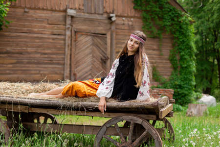 Beautiful Ukrainian woman dressed in embroidery sitting on a wooden cartの写真素材