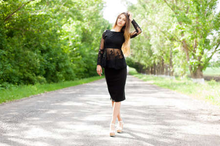 Beautiful slender Ukrainian woman in stylish black clothes on the asphalt old roadの写真素材