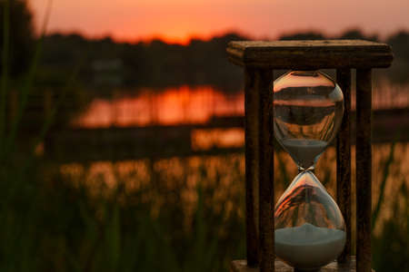 hourglass count down time against a red sunset backgroundの写真素材