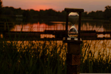 hourglass count down time against a red sunset backgroundの写真素材
