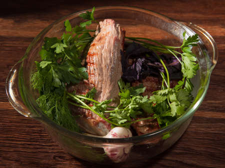 steak folded in a glass pan with dill basil garlic cilantroの写真素材