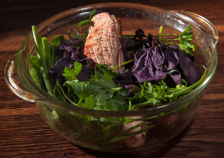 lightly cooked steak with basil dill cilantro in a glass panの写真素材