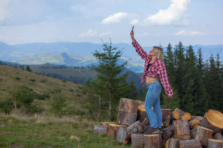 girl in stylish clothes high in the carpathians takes a selfie for social networksの写真素材