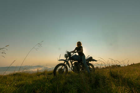 girl on a motorcycle high in the mountains stopped to rest at dawn travelsの写真素材