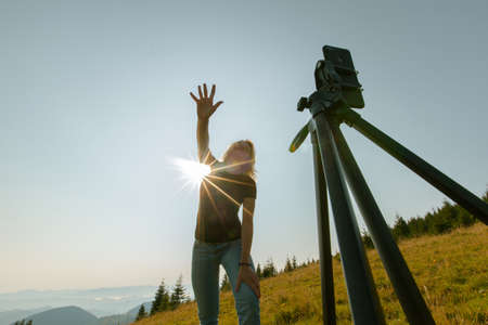 girl takes a selfie on a smartphone high in the mountains the phone is mounted on a tripodの写真素材