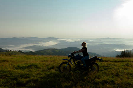 girl on a motorcycle high in the mountains stopped to rest at dawn travelsの写真素材