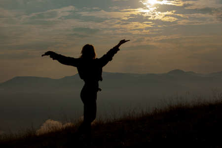 silhouette of a girl in the mountains on a background of clouds skyの写真素材