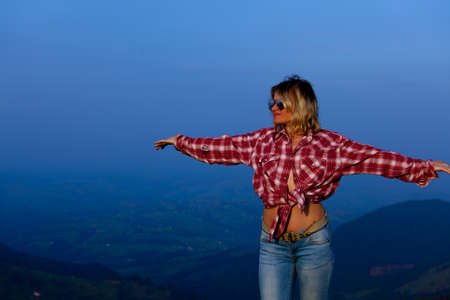 girl in a red plaid shirt posing against the backdrop of a mountain in a blue hazeの写真素材