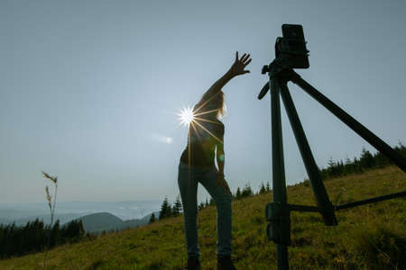 girl takes a selfie on a smartphone high in the mountains the phone is mounted on a tripodの写真素材