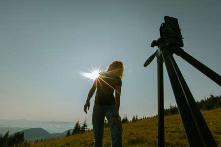 girl takes a selfie on a smartphone high in the mountains the phone is mounted on a tripodの写真素材