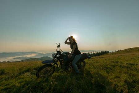 girl on a motorcycle high in the mountains stopped to rest at dawn travelsの写真素材
