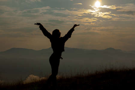 silhouette of a girl in the mountains on a background of clouds skyの写真素材