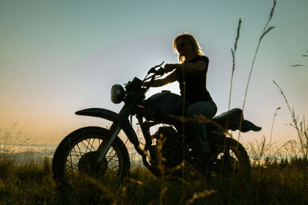 girl on a motorcycle high in the mountains stopped to rest at dawn travelsの写真素材