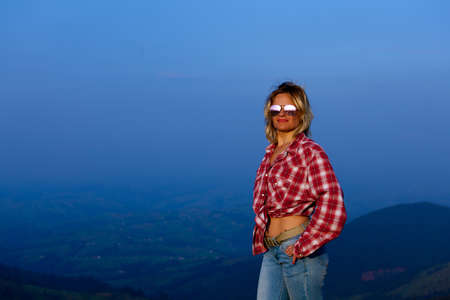 girl in a red plaid shirt posing against the backdrop of a mountain in a blue hazeの写真素材