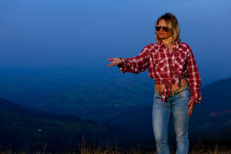 girl in a red plaid shirt posing against the backdrop of a mountain in a blue hazeの写真素材