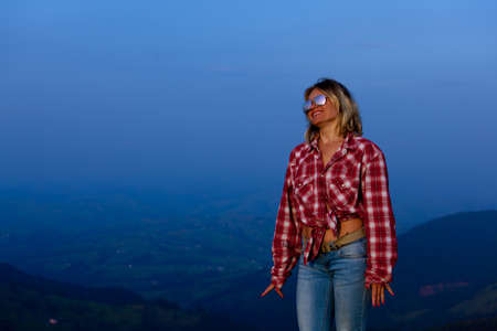 girl in a red plaid shirt posing against the backdrop of a mountain in a blue hazeの写真素材