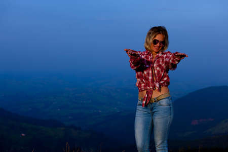 girl in a red plaid shirt posing against the backdrop of a mountain in a blue hazeの写真素材