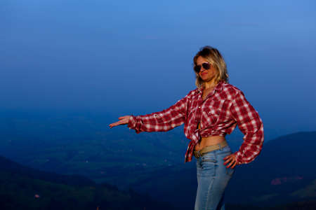 girl in a red plaid shirt posing against the backdrop of a mountain in a blue hazeの写真素材