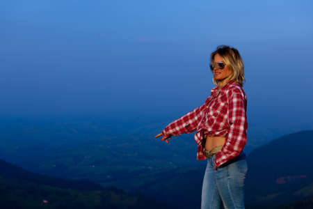 girl in a red plaid shirt posing against the backdrop of a mountain in a blue hazeの写真素材