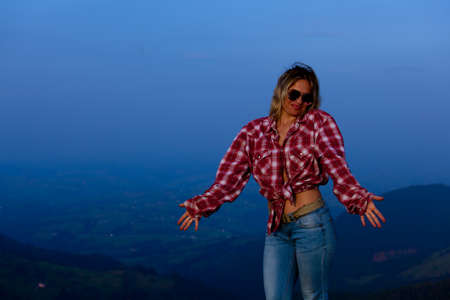 girl in a red plaid shirt posing against the backdrop of a mountain in a blue hazeの写真素材