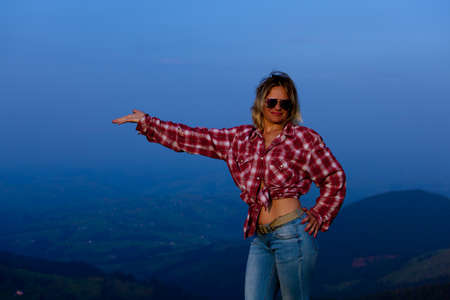 girl in a red plaid shirt posing against the backdrop of a mountain in a blue hazeの写真素材
