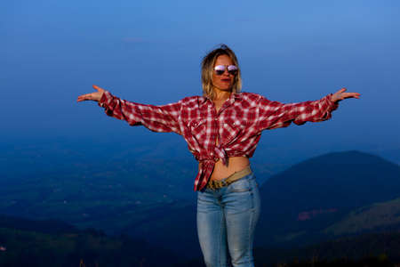 girl in a red plaid shirt posing against the backdrop of a mountain in a blue hazeの写真素材