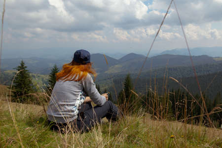 on a bright sunny summer day girl sits on the grass in the carpathian mountainsの写真素材