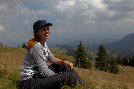 on a bright sunny summer day girl sits on the grass in the carpathian mountainsの写真素材