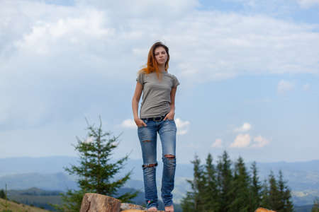 girl in a t-shirt and jeans posing in the summer high in the carpathian mountainsの写真素材