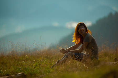 on a bright sunny summer day girl sits on the grass in the carpathian mountainsの写真素材
