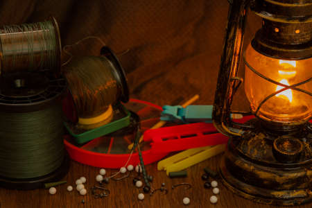 fishing line, hooks, sinkers, tools illuminated by an antique kerosene lampの写真素材